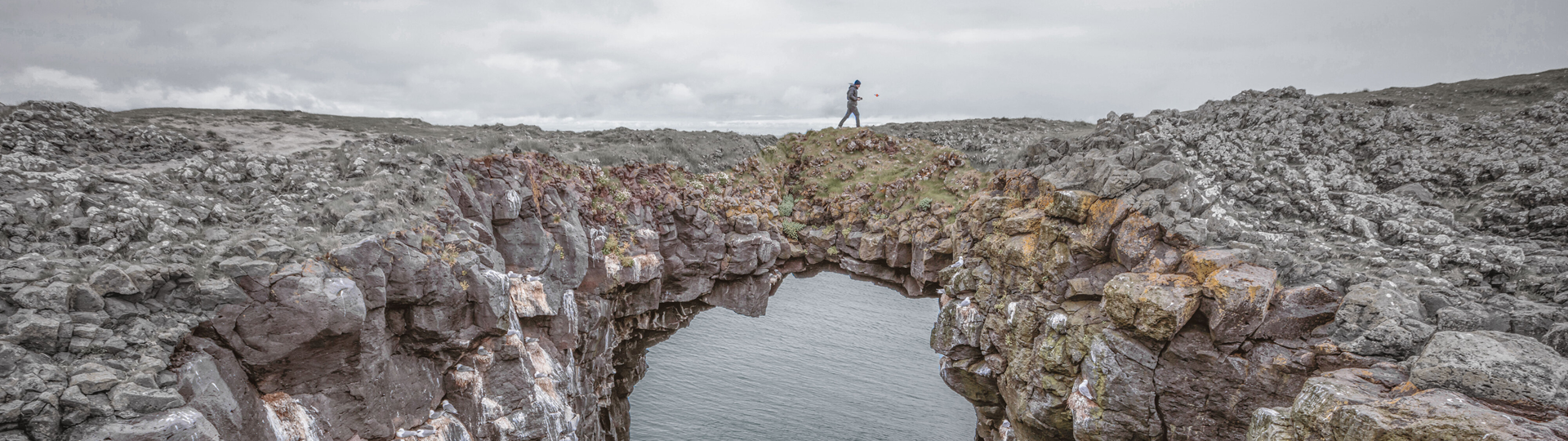person walking across a rock formation bridge