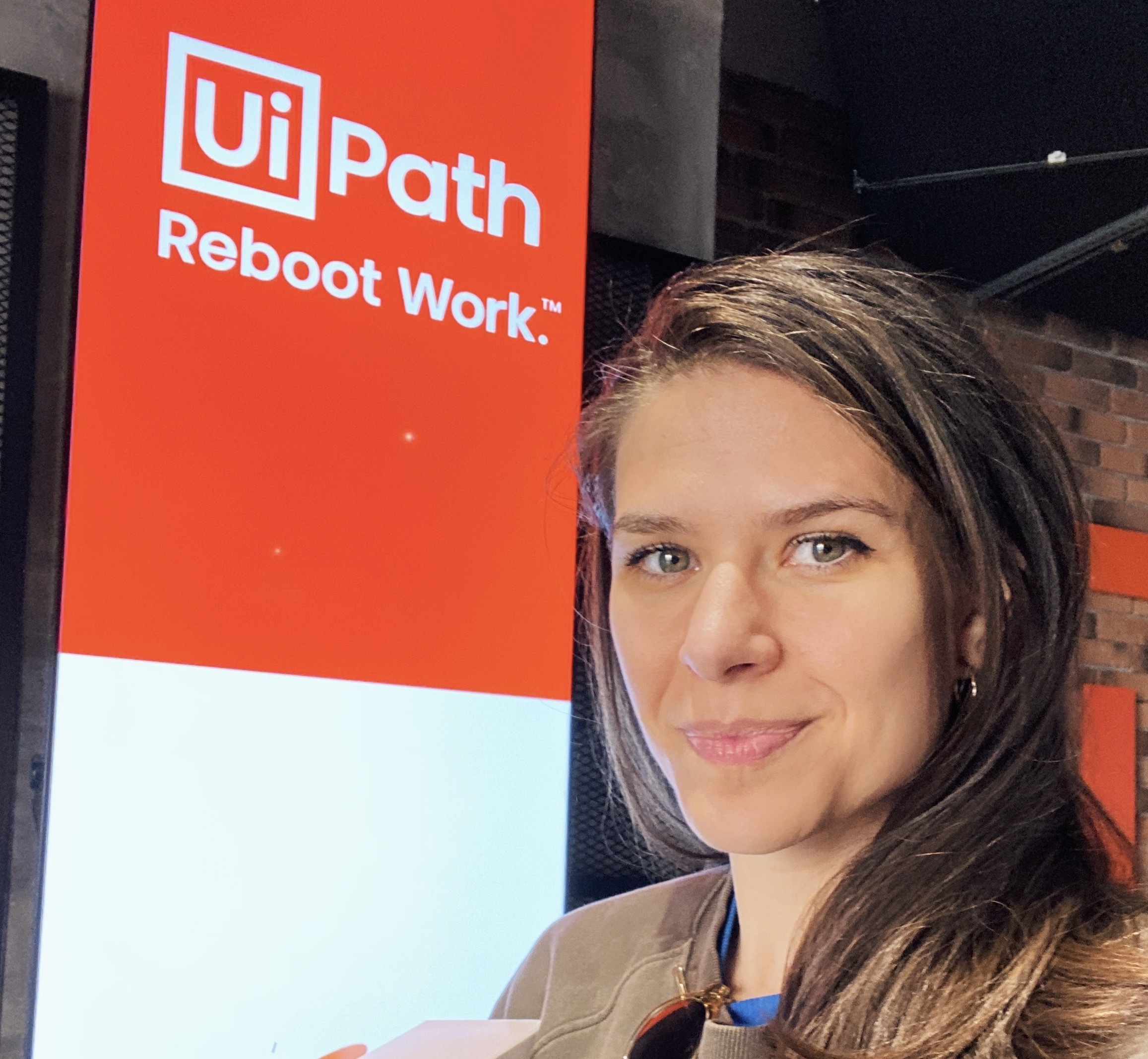 A selfie of Ioana Teleanu in front of a UiPath branded screen
