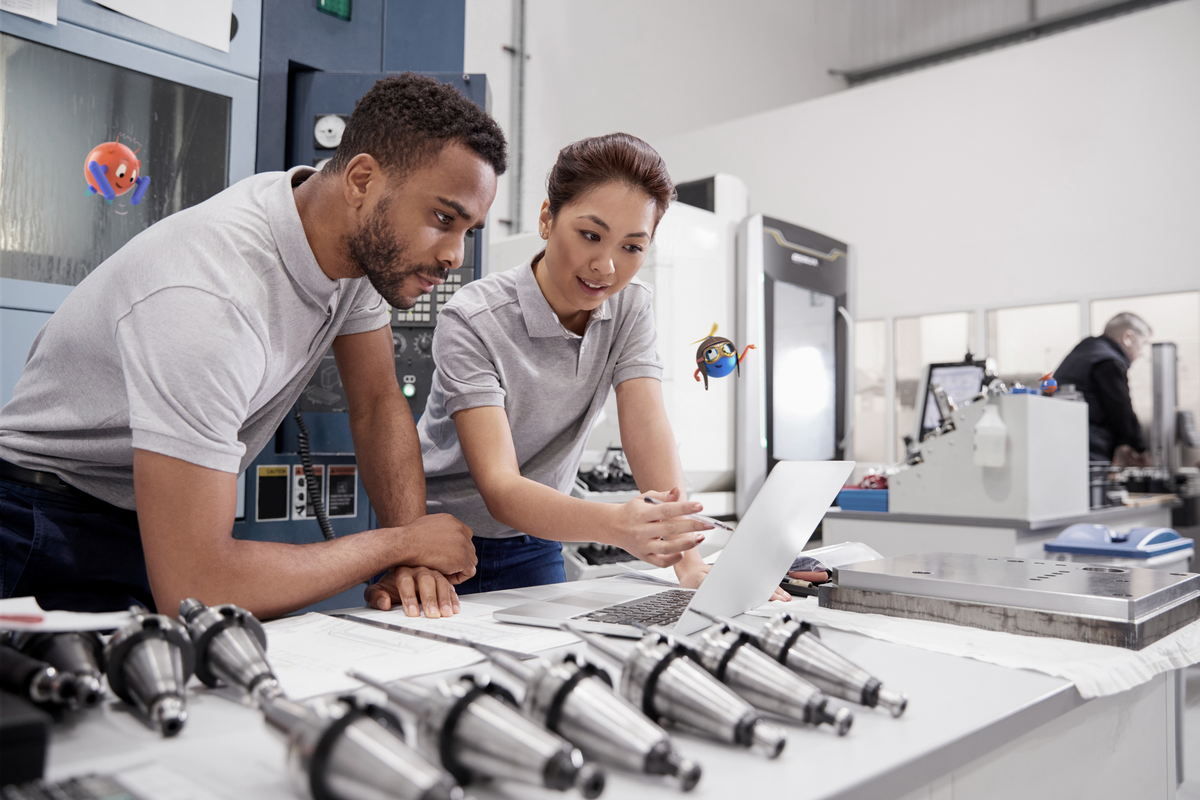 two people standing at a desk looking at a laptop manufacturing