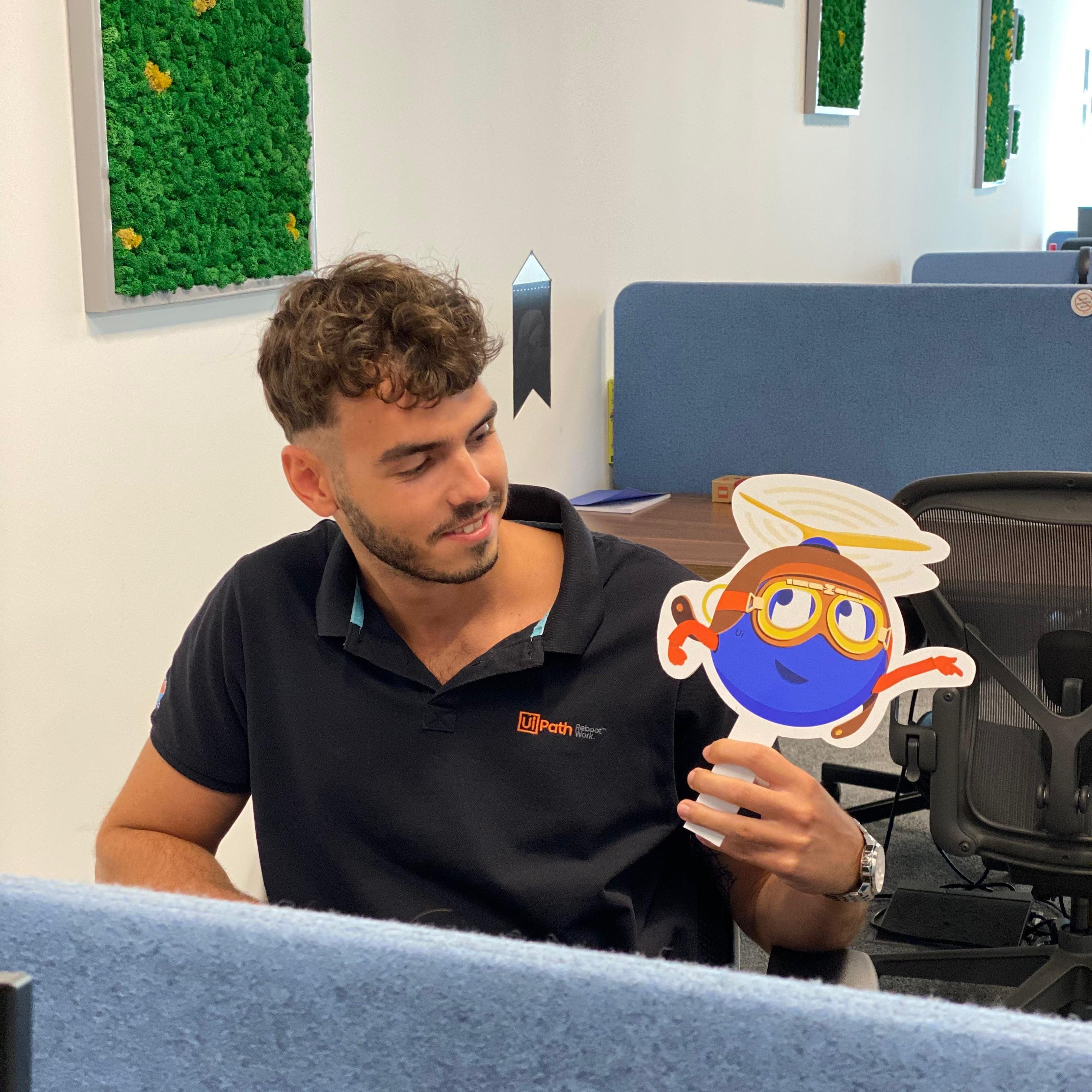 Intern Bogdan holding a UiPath robot cut-out