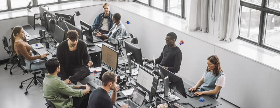 group of people in an office sitting around computers