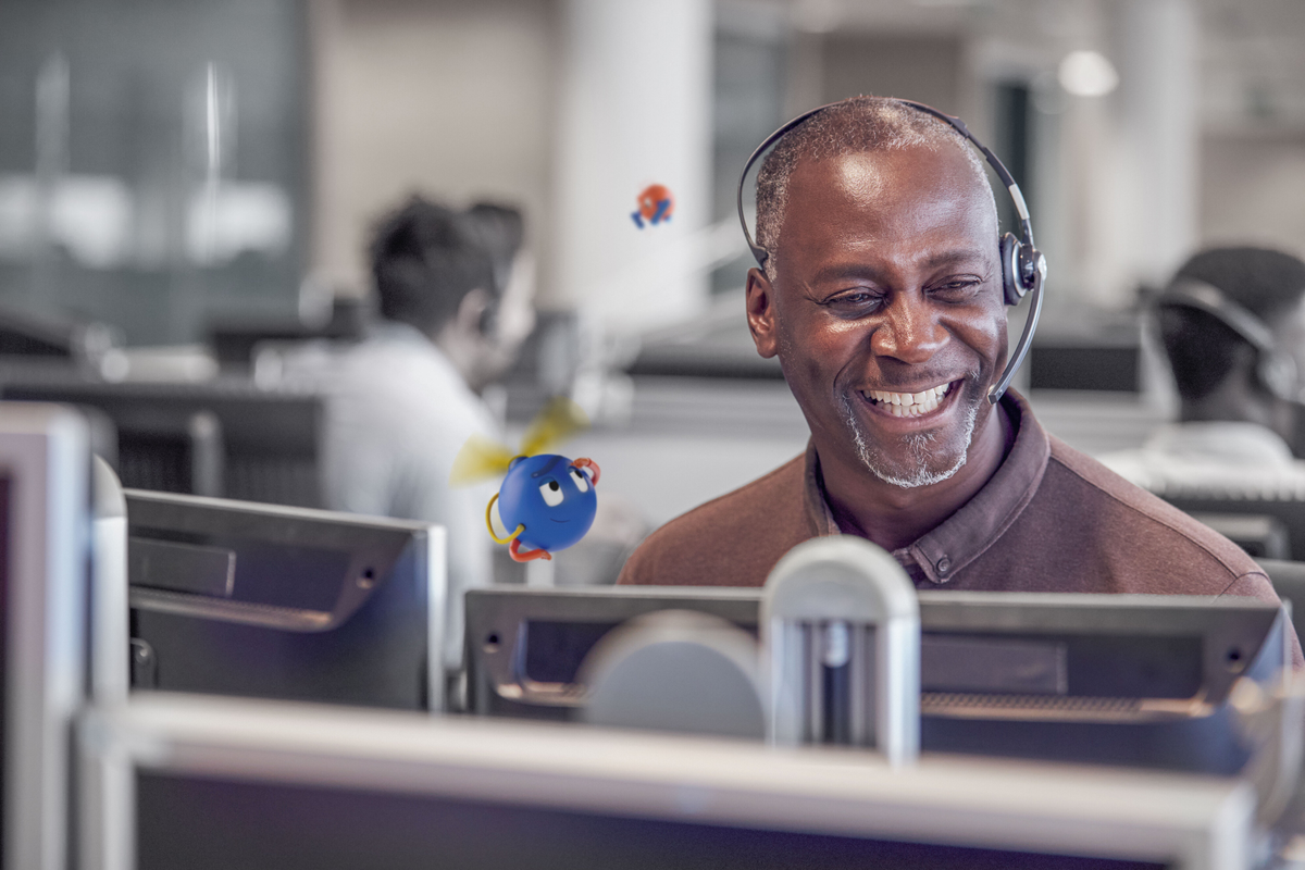 smiling man sitting in front of a monitor