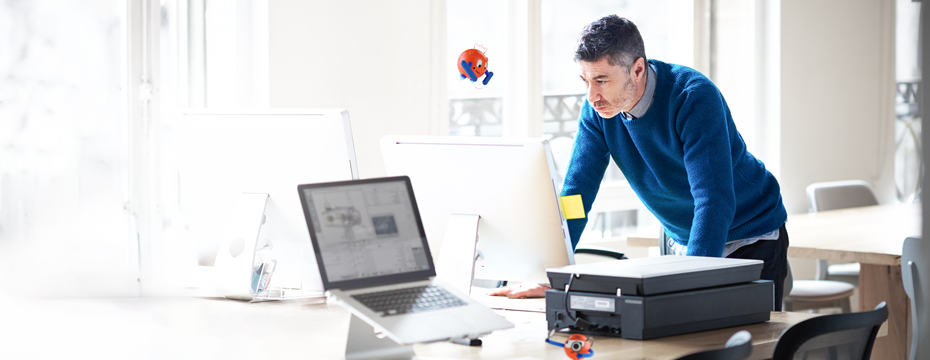 man standing at a desk looking at a computer