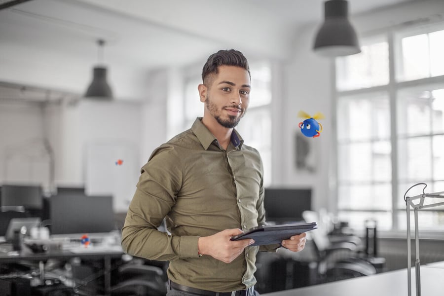 smiling man standing holding a laptop