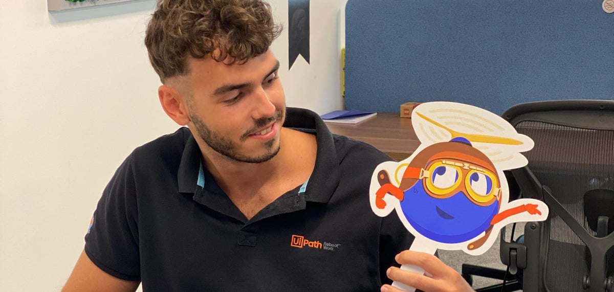 UiPath intern Bogdan holding a UiPath robot sign