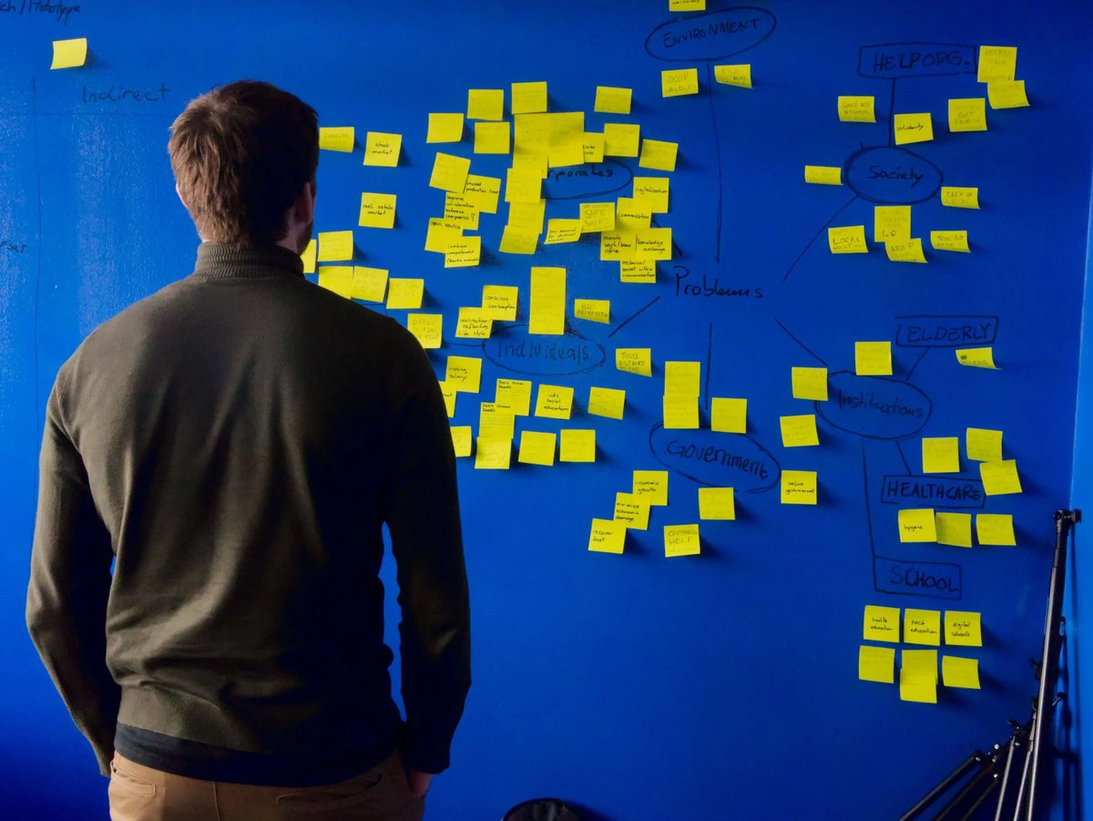 man looking at sticky notes on wall