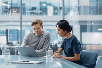 two co-workers working on a laptop at a table