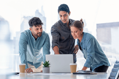 three coworkers looking at a laptop