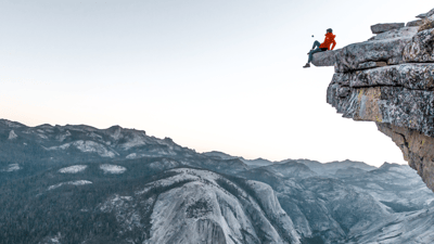 person sitting on a mountain overhang