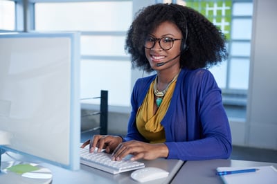 Portrait-of-a-smiling-customer-service-representative-with-an-afro-at-the-computer-using-headset