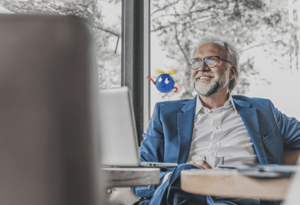 smiling man sitting at a table with a laptop