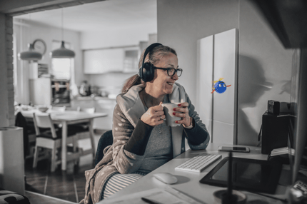 woman holding a cup smiling with headphobes