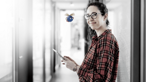 a portrait photo of a woman using a phone, together with a UiPath robot flying around her