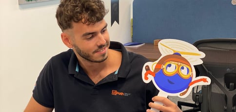 UiPath intern Bogdan holding a UiPath robot sign
