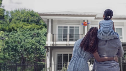 a photo of a family hugging and looking at their house