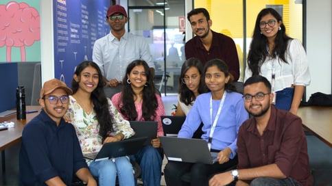 A diverse group of Product Support interns posing for a group photo, collaborating in a modern office setting.