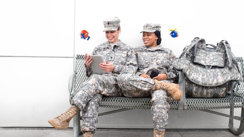 Two female soldiers sitting on the bench looking at files