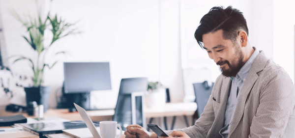 man at desk with laptop and phone