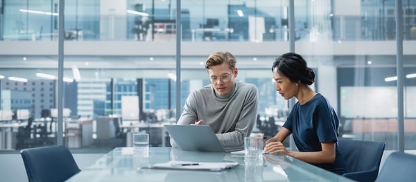 two co-workers working on a laptop at a table