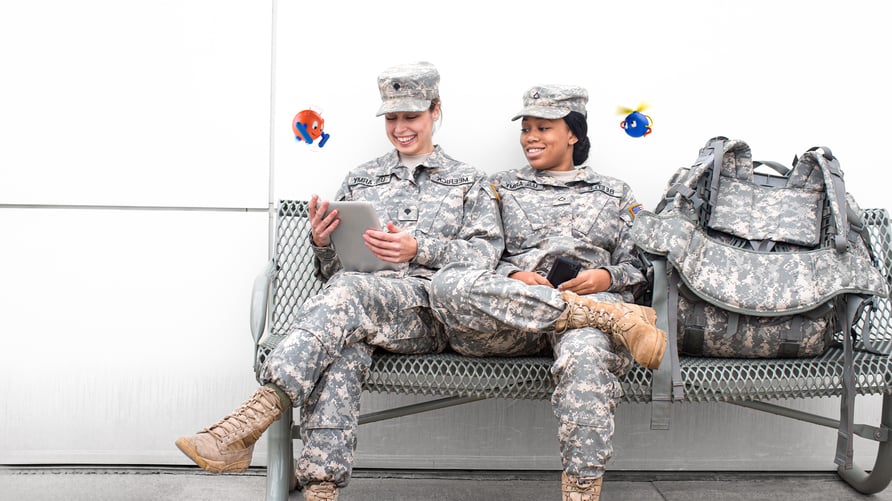 Two female soldiers sitting on the bench looking at files